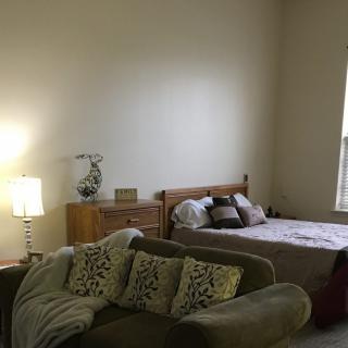 A cozy bedroom with a bed, couch, and lamp.