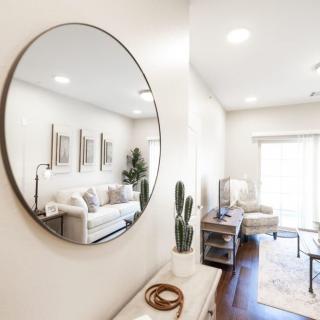 A modern, minimalist living room interior with a round mirror and cactus decor.