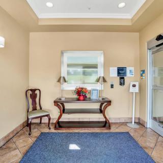 An inviting lobby entrance with a decorative table and chair set beneath a mirror.