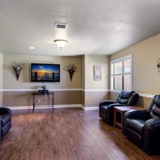 A cozy living room with leather chairs, a television, and a hardwood floor.