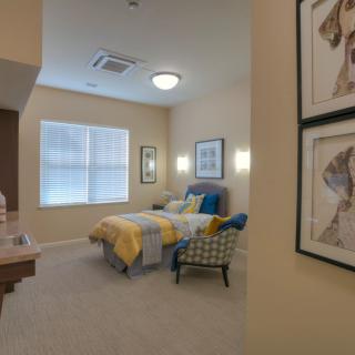 A cozy bedroom with a neatly made bed, decorative pillows, and framed art on the walls.