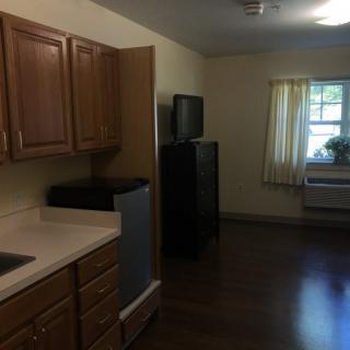 A small kitchen area with wooden cabinets and a window with curtains.