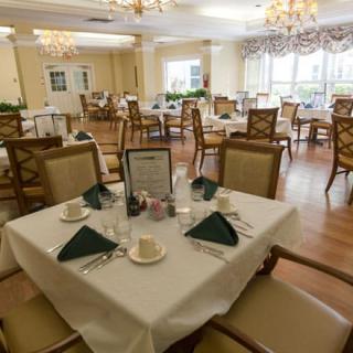 An elegant dining room with neatly arranged tables and chairs under chandeliers.