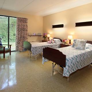 A hospital room with two patient beds and a window view.