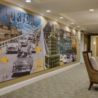 A hallway features a large mural with vintage cars and architectural elements.