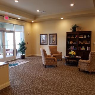 A cozy lobby seating area with chairs, a bookshelf, and decorative elements.