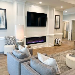 A modern living room featuring a large television, contemporary fireplace, and stylish seating area.
