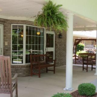 A cozy outdoor patio area with wooden furniture, hanging plants, and brick walls.