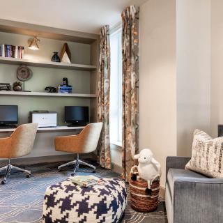 A modern home office with dual workstations, cozy chairs, and stylish decor.