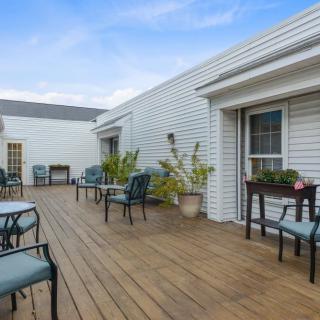 A spacious outdoor deck area with chairs and tables, adorned with potted plants.
