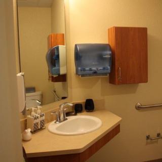 A clean and organized bathroom with a sink, mirror, and paper towel dispenser.