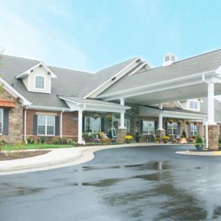 A welcoming building entrance with a covered driveway and landscaped surroundings.