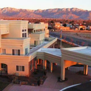 A modern building with a mountain range in the background during sunset.