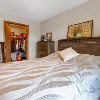 A cozy bedroom with a large bed and an open closet in the background.