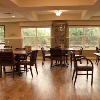 A cozy dining area featuring wooden tables and chairs, illuminated by natural light.