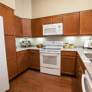 A modern kitchen with wooden cabinets and appliances, including a microwave, oven, and refrigerator.