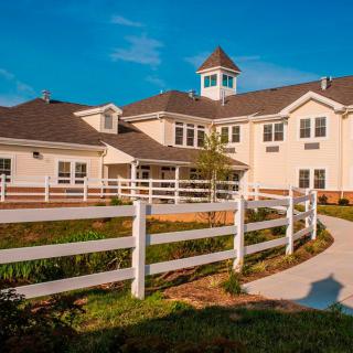 A large residential house with a white fence and a clear blue sky.