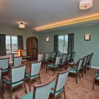 A well-arranged conference room with chairs facing a small podium and large windows allowing natural light.