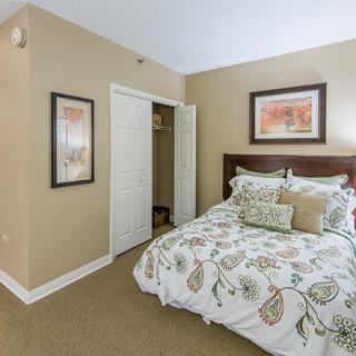 A cozy bedroom with floral bedding, framed artwork, and a small closet.