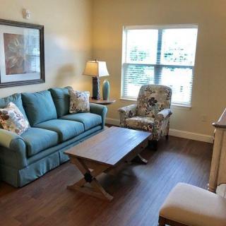A cozy living room with a blue sofa, patterned armchair, and coffee table.