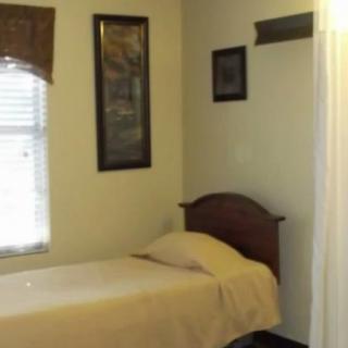 A small bedroom with a single bed, a window, and wall decorations.