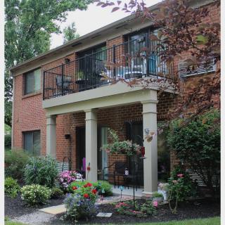 A charming brick house with a balcony and a beautifully landscaped garden.