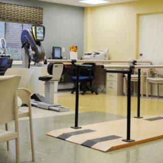 A rehabilitation room equipped with parallel bars and exercise equipment for physical therapy.