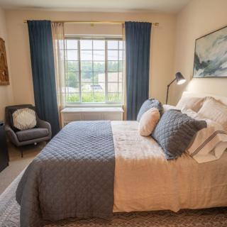 A cozy bedroom with a well-made bed, blue curtains, and elegant decor.
