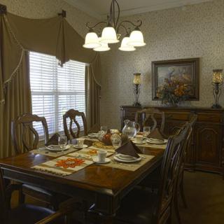 A beautifully set dining room with an elegant table and chairs, adorned by a chandelier, ready for a meal.