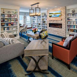 A modern living room with a cozy seating area, bookshelves, and a fireplace.
