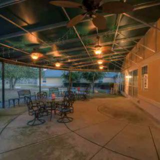 A tranquil backyard patio with a covered seating area illuminated by warm evening lights.