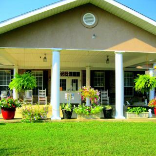 A charming house with a spacious porch, adorned by potted plants and surrounded by a well-maintained lawn.