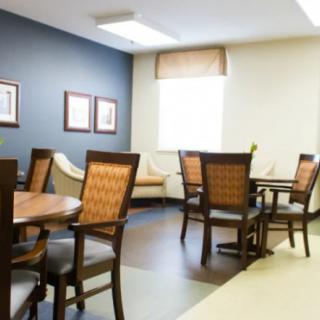 A well-lit dining area featuring several tables and chairs, decorated with framed artwork on the walls.