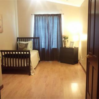 A cozy nursery room featuring a crib and warm wooden flooring with soft lighting.
