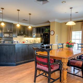 A cozy kitchen and dining area with dark cabinets, a wooden table, and pendant lighting.
