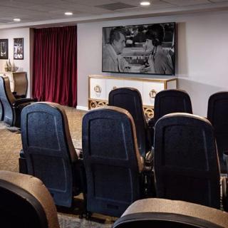 A cozy home theater setup with comfortable seating and a large projector screen displaying a movie.