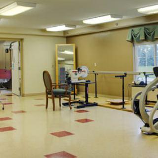 A rehabilitation room with various exercise equipment and furniture.
