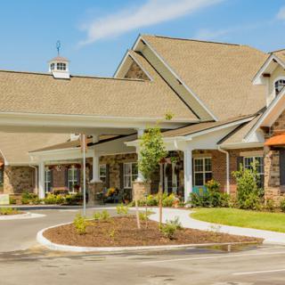 A modern residential building with a landscaped entrance on a sunny day.