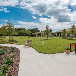 A scenic view of a landscaped garden with pathways, benches, and a partly cloudy sky.