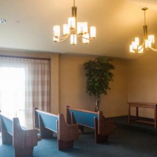 A well-lit interior room with pew-style seating and a potted plant.