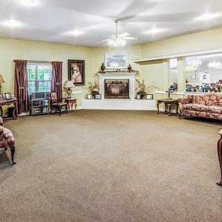 A spacious living room with traditional decor, featuring a central fireplace and comfortable seating arrangements.