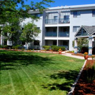 A well-maintained apartment complex with lush green lawns and surrounding trees.