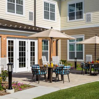 Outdoor seating area with tables and umbrellas on a patio outside a building.