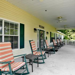 A covered porch featuring multiple rocking chairs lined up for relaxation.