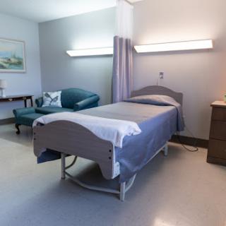 A well-lit and organized patient room in a hospital, featuring a bed and comfortable seating.