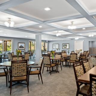A spacious dining room with modern decor, featuring multiple tables and chairs.