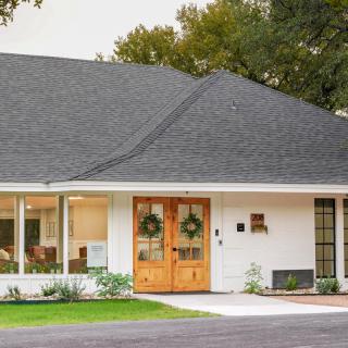 A suburban house with a neatly landscaped front yard and large windows.