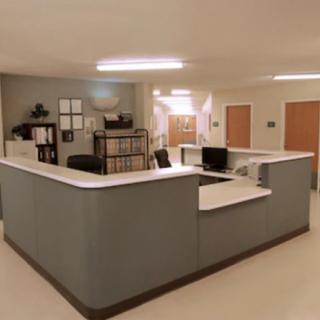 A reception area with a large desk, computers, and organized shelving.