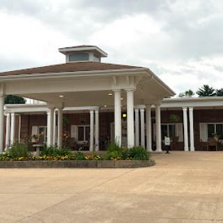 A welcoming entrance to a building featuring classic architectural elements and landscaped gardens.