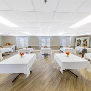 A brightly lit banquet room with white tablecloth-covered tables and decorations.